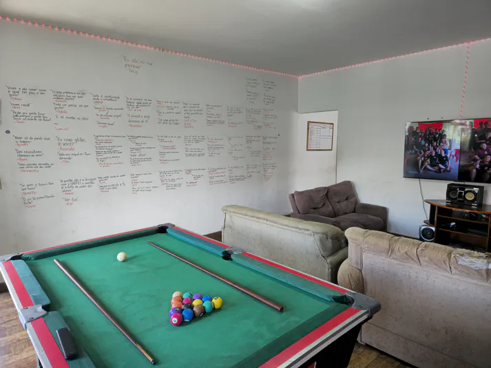 Outro ângulo da sala de estar destacando a decoração temática universitária e área de convivência