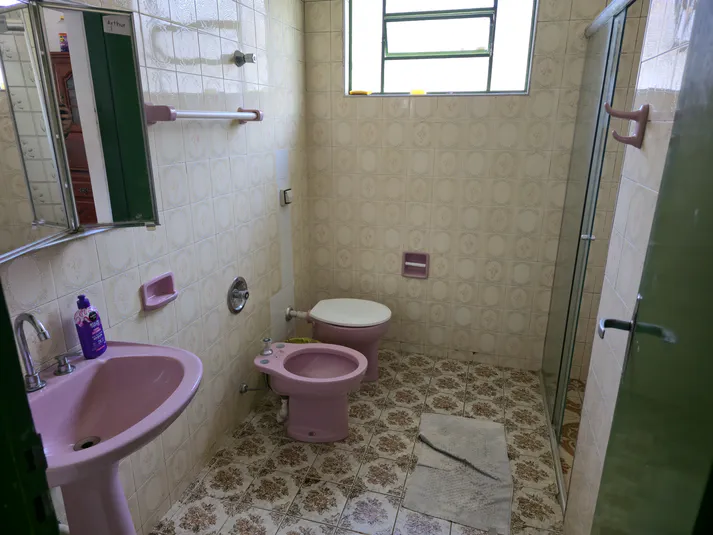 Banheiro privativo anexo à suíte dupla, com acabamento moderno, espelho e box de vidro